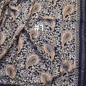 Puede incluir: Un textil azul marino oscuro con un intrincado estampado de cachemira en hilo dorado y blanco. El diseño presenta grandes motivos de cachemira y delicadas enredaderas florales. El borde está acabado con un borde decorativo. El texto "#1" es visible.