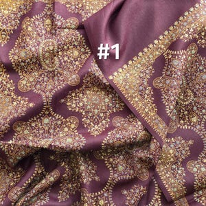 May include: A burgundy textile with an intricate gold paisley pattern and a gold border. The fabric is folded, revealing the texture and design. The number "#1" is printed in white.