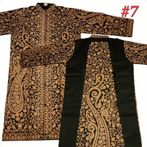 Op de afbeelding: Zwart en goud geborduurde tuniek met lange mouwen. De tuniek heeft ingewikkelde bloemen- en paisley-patronen. Het kledingstuk wordt getoond met de voor- en achterkant zichtbaar, waarbij het gedetailleerde ontwerp wordt benadrukt. Het nummer 7 is rechtsboven zichtbaar.