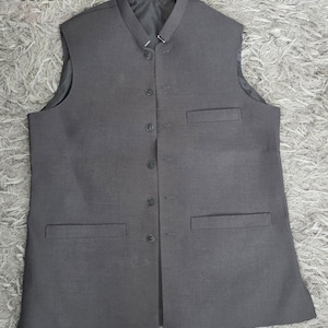 May include: A gray vest with a mandarin collar and a button-up front. The vest has two front pockets and a tailored fit. The number "#1" is in the top left corner. This formal vest is suitable for various occasions.