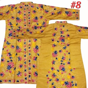 Op de afbeelding: Mosterdgele geborduurde tuniek met een mandarijnkraag en lange mouwen. De tuniek is versierd met bloemenborduurwerk in roze, blauwe en gele tinten. Het kledingstuk heeft een knoopsluiting aan de voorkant en het nummer "#8" is rechtsboven zichtbaar.
