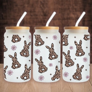 May include: Three frosted glass tumblers with bamboo lids and clear straws. Each tumbler features a white background with a repeating pattern of brown and black leopard print bunnies and pink flowers.