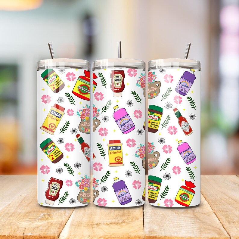 May include: Three white stainless steel tumblers with lids and straws. The tumblers are decorated with a pattern of pink flowers, green leaves, and various food and beverage items, including bottles of hot sauce, ketchup, and cleaning products. The text "Amor Madre" and "Fabulous" are visible on some of the items.