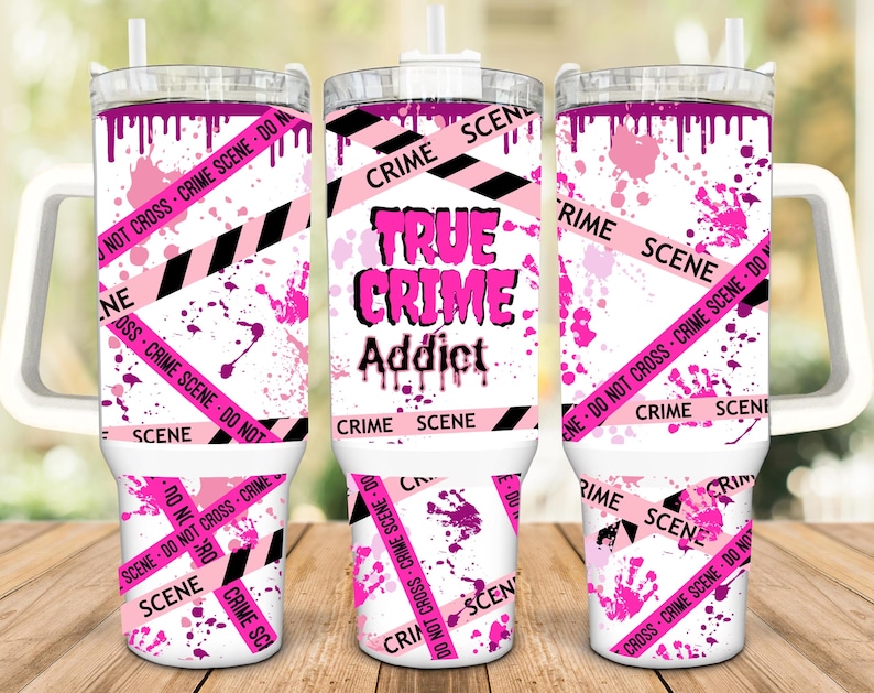 May include: A white tumbler with a pink and black crime scene tape design. The tumbler has a handle and a lid. The text "True Crime Addict" is printed on the tumbler.