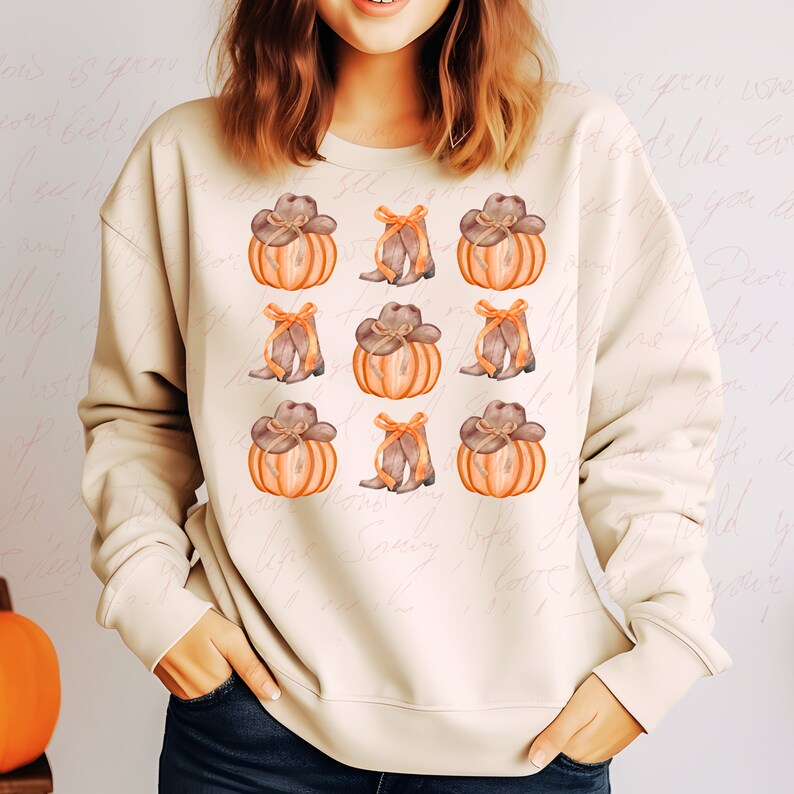 May include: A beige sweatshirt with a pattern of orange pumpkins and brown cowboy boots. Each pumpkin has a brown cowboy hat on top.