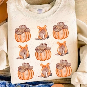 May include: A beige sweatshirt with a pattern of orange pumpkins with brown cowboy hats and brown boots with bows. The pumpkins are watercolor style.