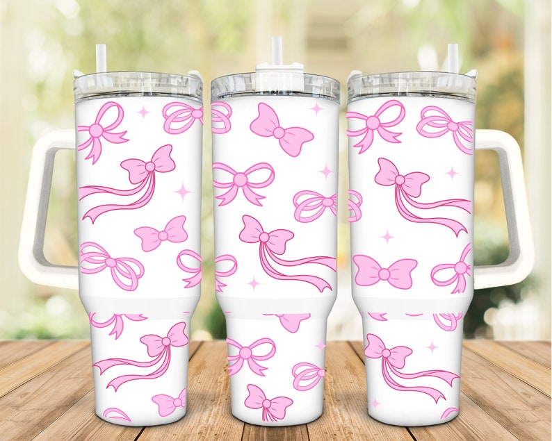 May include: Three white stainless steel tumblers with pink bows and ribbons on a white background. The tumblers have lids and handles.