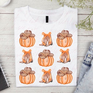 May include: A white t-shirt with a repeating pattern of orange pumpkins with brown cowboy hats and brown cowboy boots with a bow.