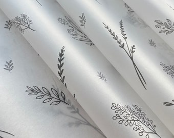Könnte beinhalten: Weißes Seidenpapier mit einem sich wiederholenden Muster aus schwarzen floralen Designs. Das Papier ist dreifach gefaltet und zeigt das Muster auf jeder Schicht.