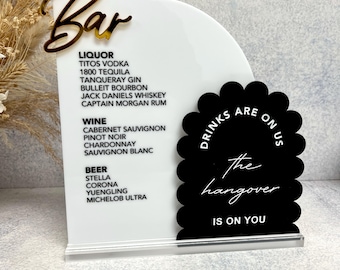 May include: White acrylic sign with black text listing various liquor, wine, and beer options. A black circle with white text reads "Drinks are on the hangover is on you".