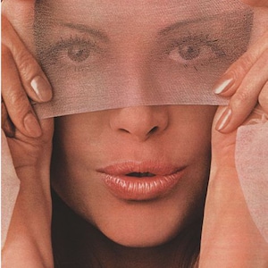 May include: A woman's face with a sheer fabric covering her eyes. Her lips are slightly parted and her expression is soft and inviting.