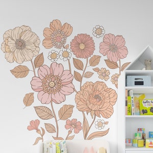 Puede incluir: Una estantería blanca con una parte superior en forma de casa, con un zorro de juguete blanco y un perro de juguete blanco sentados delante. La estantería tiene tres estantes y un cajón. La pared detrás de la estantería tiene una gran calcomanía floral con flores rosas y naranjas.