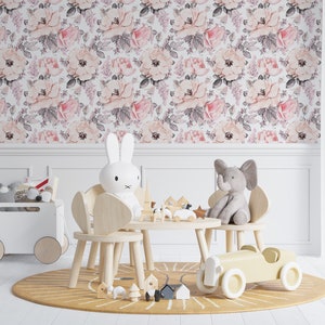May include: A playroom with a floral wallpaper featuring pink and white flowers. There are two wooden chairs with stuffed animals, a wooden table with a yellow toy car, and a white toy chest with a toy airplane on top.