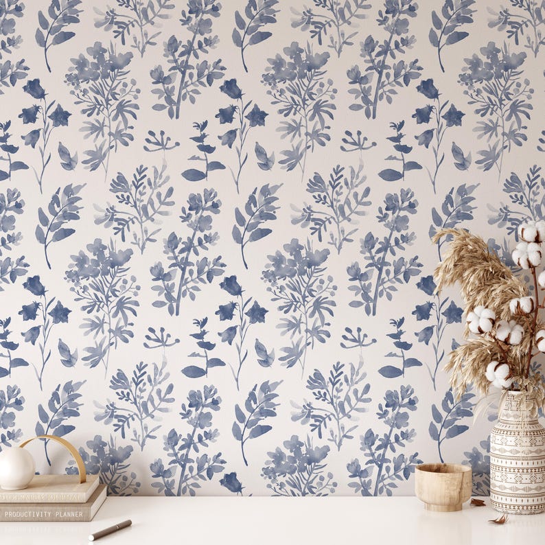 K&ouml;nnte beinhalten: Eine Aquarell-Blumen-Tapete mit wei&szlig;em Hintergrund und blauen Blumenmustern. Die Tapete zeigt ein sich wiederholendes Muster aus blauen Blumen und Bl&auml;ttern.
