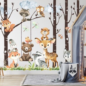 May include: A white wall with a brown tree mural featuring a variety of woodland animals, including a deer, a bear, a raccoon, a fox, a squirrel, an owl, and a beaver. The mural is decorated with butterflies and dragonflies. The wall is in a nursery with a wooden bed and a white chair.