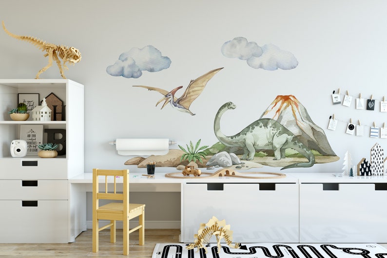 May include: A children's room decorated with dinosaur wall decals. The decals feature a green dinosaur, a flying dinosaur, and a volcano. There are also clouds and a small palm tree.