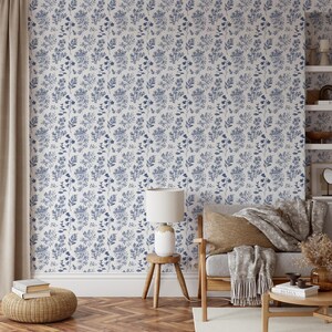 K&ouml;nnte beinhalten: Eine wei&szlig;e Tapete mit einem blauen Blumenmuster. Die Tapete befindet sich in einem Wohnzimmer mit einem Stuhl, einer Lampe und einem Beistelltisch.