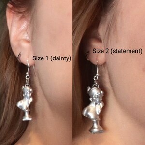 This photo shows a side-by-side of a blonde woman wearing a Sappho bust earring in the dainty size and the statement size.