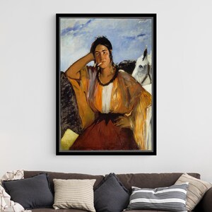 Puede incluir: Impresión artística enmarcada de una mujer con un vestido colorido, apoyada en una superficie oscura con un caballo blanco al fondo. La pintura presenta una paleta de naranja, rojo y blanco, sobre un cielo azul. La obra de arte está sobre un sofá marrón.