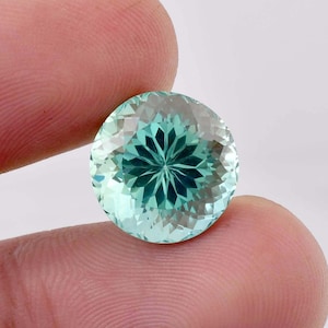 May include: A round, faceted, teal green gemstone with a starburst pattern in the centre.