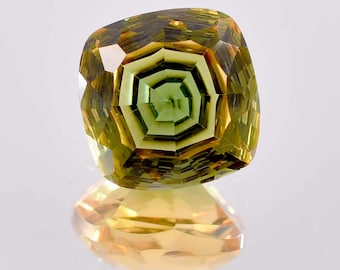 May include: A green and yellow gemstone with a faceted, cushion-shaped cut. The gemstone has a hexagonal pattern in the center.