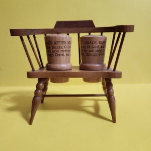 May include: A wooden chair with two small wooden salt and pepper shakers. The shakers have religious text on them. The text on the left shaker reads "GRACE AFTER ME Thee thanks, O Lord, we have received through Christ, our." The text on the right shaker reads "GRACE BEFORE us, O Lord, and we are about to through Christ".