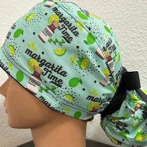 Puede incluir: Un gorro de quirófano azul turquesa con una cinta negra. El gorro tiene un patrón repetido de limas, botellas y el texto "Margarita Time" con un "zzz" debajo.