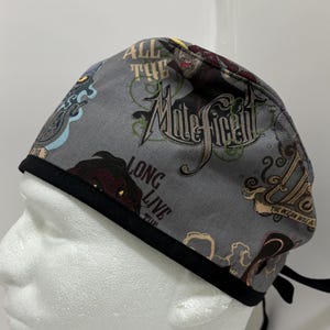 May include: Gray scrub hat with a black trim and a print of the Disney character Maleficent. The print includes the text "All the Maleficent Long Live the" and "The Dream Will Arise".