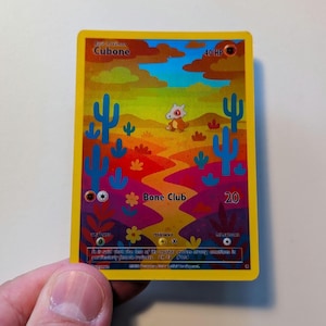 Puede incluir: Una carta coleccionable de Pokémon Cubone con una ilustración con temática desértica. La carta presenta un personaje Cubone, cactus y el texto "Bone Club". La tarjeta tiene un borde amarillo e incluye texto sobre las habilidades y el trasfondo del personaje.