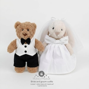 May include: A brown plush teddy bear wearing a white vest, black bow tie, and black shorts, standing next to a cream-colored plush rabbit wearing a white dress and a sheer veil. Text below reads: Xanh La Handmade, Bride and groom outfits.