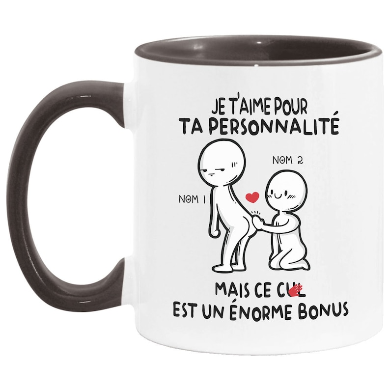 May include: White ceramic coffee mug with a black handle and a black rim. The mug has a graphic of two stick figures with the text "JE T'AIME POUR TA PERSONNALIT&Eacute; MAIS CE CUL EST UN &Eacute;NORME BONUS" printed on it.