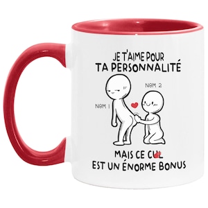 May include: White ceramic mug with a red rim and handle. The mug features a cartoon illustration of two stick figures with the text "JE T'AIME POUR TA PERSONNALIT&Eacute; MAIS CE CUL EST UN &Eacute;NORME BONUS".