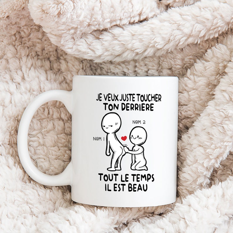Puede incluir: Taza de cer&aacute;mica blanca con una ilustraci&oacute;n en blanco y negro de dos figuras de palo. El texto en la taza dice "JE VEUX JUSTE TOUCHER TON DERRIERE NOM 1 NOM 2 TOUT LE TEMPS IL EST BEAU".