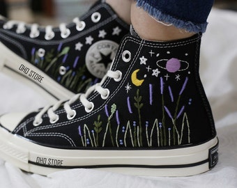 May include: Black high-top sneakers with embroidered celestial and floral designs. The sneakers feature a white sole and laces, with a design of a moon, stars, and a planet. The text "OHO STORE" is visible on the side.