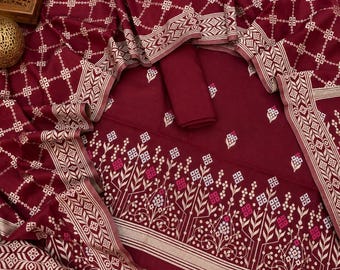 May include: A deep maroon fabric set featuring a white geometric grid pattern and a floral border design. The textile includes a solid maroon piece and a larger section with intricate white and pink botanical motifs, finished with decorative tassels.