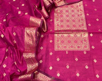 May include: A vibrant fuchsia fabric featuring a woven gold metallic pattern. The material displays a central rectangular panel with intricate floral and geometric motifs, surrounded by scattered gold diamond shapes and a wide decorative border.