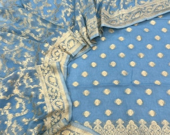 May include: A light blue fabric featuring intricate gold metallic embroidery. The textile displays a repeating pattern of small gold floral motifs across the main section, complemented by a wide, ornate border with detailed scrolling leaf designs.