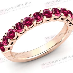 May include: A rose gold band ring with a row of red ruby stones.