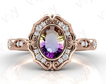 Puede incluir: Un anillo de compromiso de oro rosa con una gran piedra preciosa de forma ovalada. La piedra preciosa es una amatista multicolor con tonos de púrpura, amarillo y verde. El anillo está engastado en un delicado diseño de filigrana con pequeños diamantes que rodean la piedra preciosa.