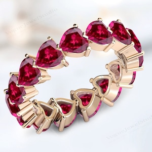 Può includere: Una fascia di eternità in oro rosa con una fila continua di pietre preziose di rubino a forma di cuore.