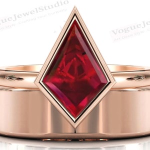May include: A rose gold wedding band set with a large, red, faceted gemstone in a diamond-shaped setting. The gemstone is surrounded by a thin, rose gold band.
