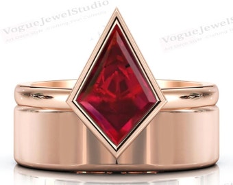 May include: A rose gold wedding band set with a large, red, faceted gemstone in a diamond-shaped setting. The gemstone is surrounded by a thin, rose gold band.