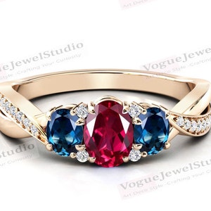 May include: A gold ring with a ruby and two blue gemstones set in a twisted band with small diamonds.