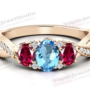 Pode incluir: Um anel de ouro com uma gema oval azul e duas gemas ovaladas vermelhas. O anel é adornado com pequenos diamantes na banda.