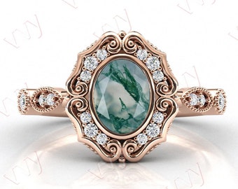 May include: A rose gold ring with a green agate oval gemstone surrounded by a halo of small diamonds. The ring has a vintage-inspired design with intricate details.