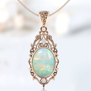 May include: A delicate gold pendant necklace features a large oval opal gemstone surrounded by a filigree design. Two small diamonds accent the top and bottom of the pendant.