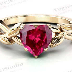 May include: A gold ring with a heart-shaped ruby gemstone set in a leafy design. The ring is crafted in an Art Deco style.