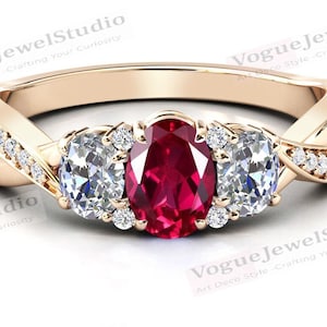 May include: A gold ring featuring a red oval gemstone and two smaller oval gemstones. The ring has a twisted band with small diamonds set into the band.