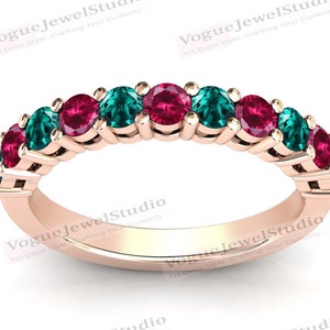 May include: A rose gold band ring with alternating emerald green and ruby red gemstones. The ring is set with a total of 10 stones.