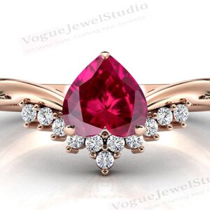 May include: A pear-shaped ruby gemstone set in a rose gold ring with a twisted band and a row of smaller diamonds around the centre stone.